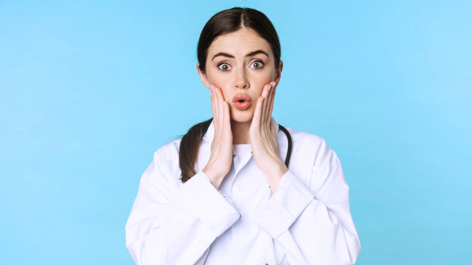 A female doctor in a white coat is making a playful or surprised facial expression.