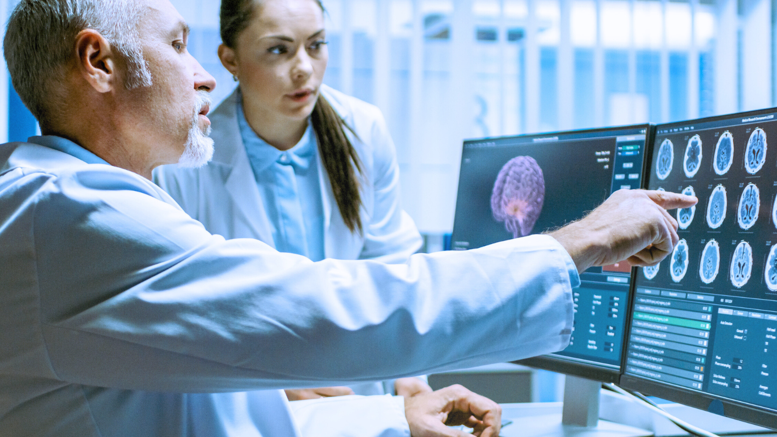 Two doctors analyzing MRI images on a computer screen in a clinical setting.