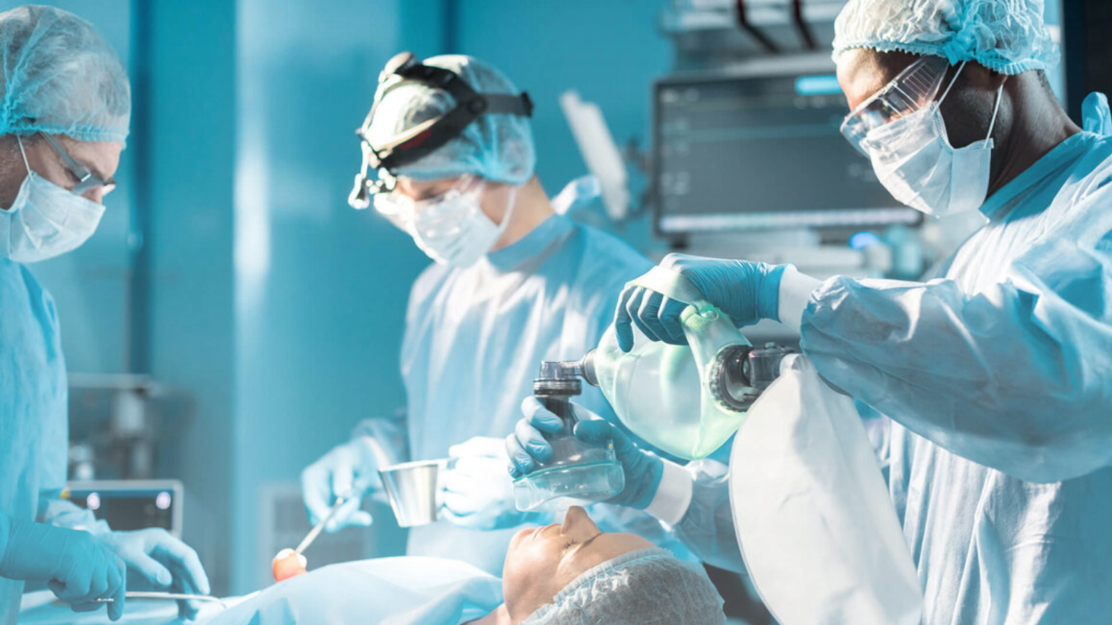 A team of medical professionals in surgical attire performing a procedure on a patient in an operating room.