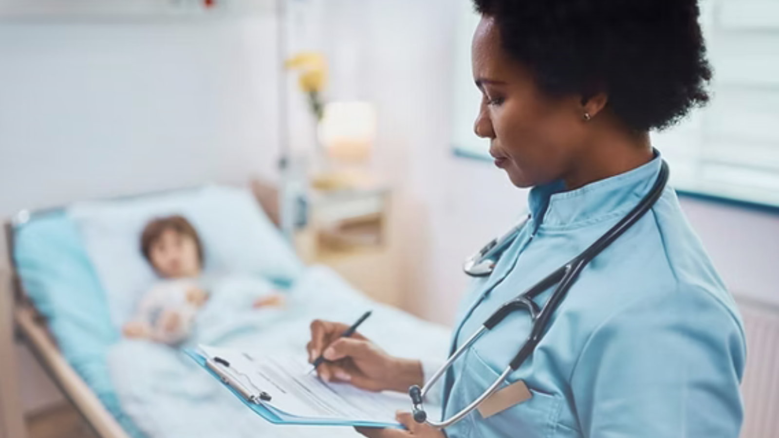 A female doctor writing notes on a clipboard in a hospital room, focused on patient care and documentation.