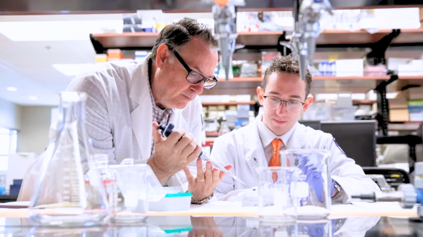 Two men in lab coats examining a sample together in a laboratory setting.